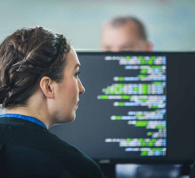 Woman looking at computer screen with code.