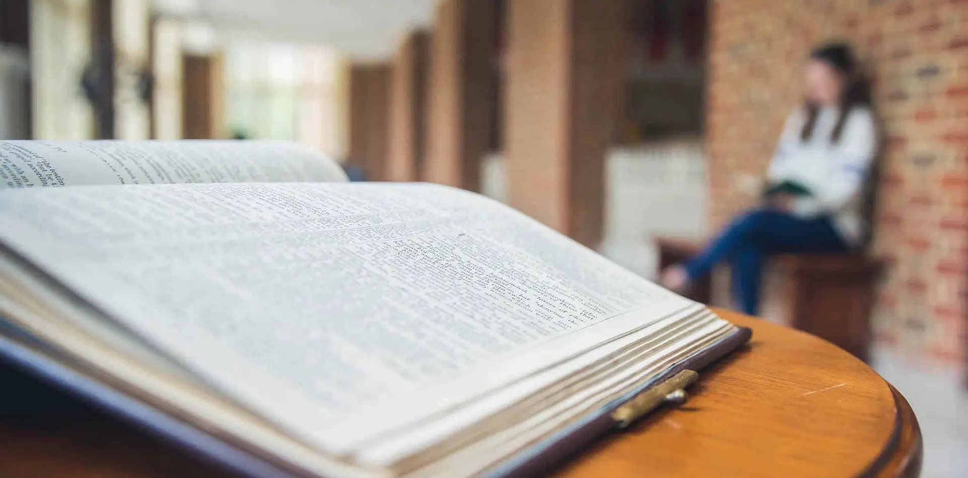 A Bible on a table with a Regent student in the background.