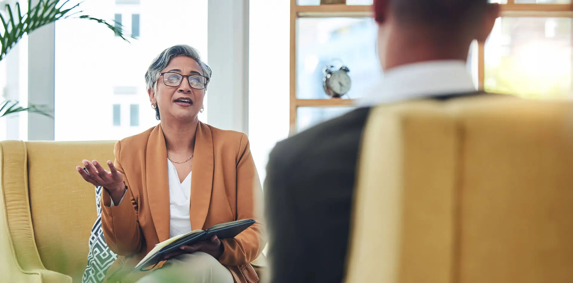 A counselor holding a notepad speaking to a client.