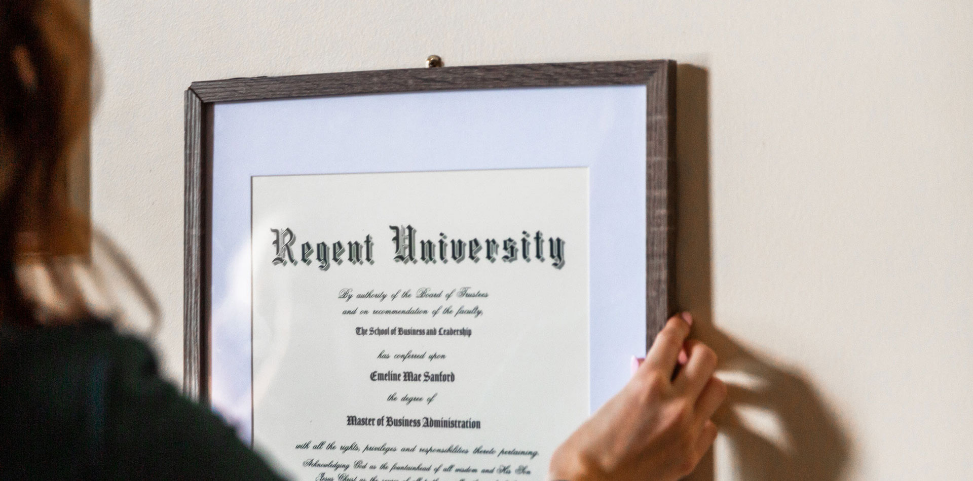 Regent Graduate hanging up their diploma.