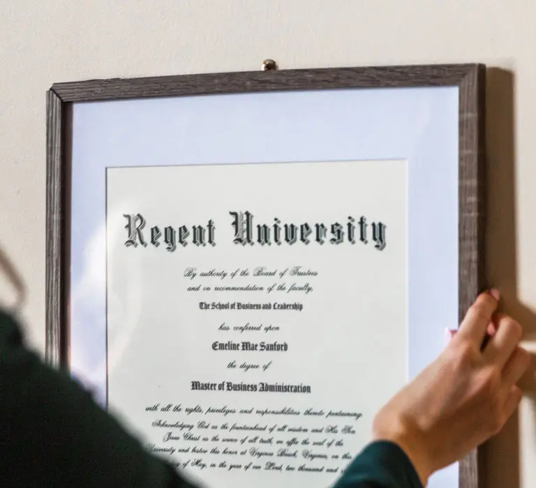 Regent Graduate hanging up their diploma.
