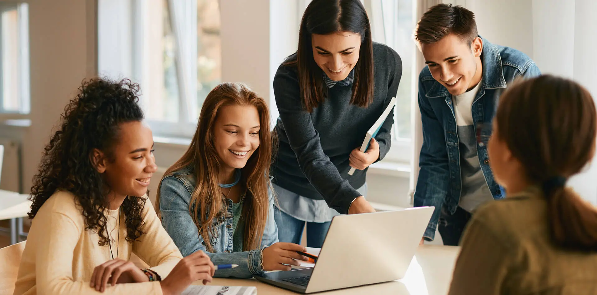 Five people in a group in front of laptop on table