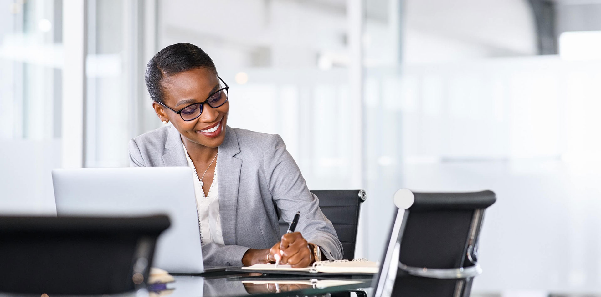Woman with laptop writing notes on desk